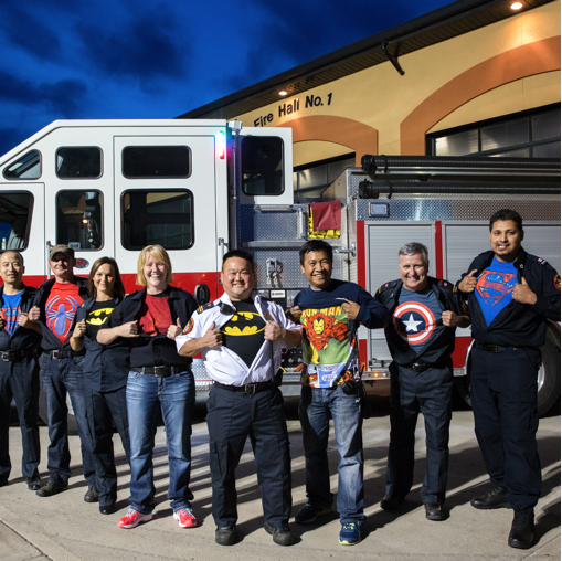 A team of emergency services personnel stand in front of a fire hall